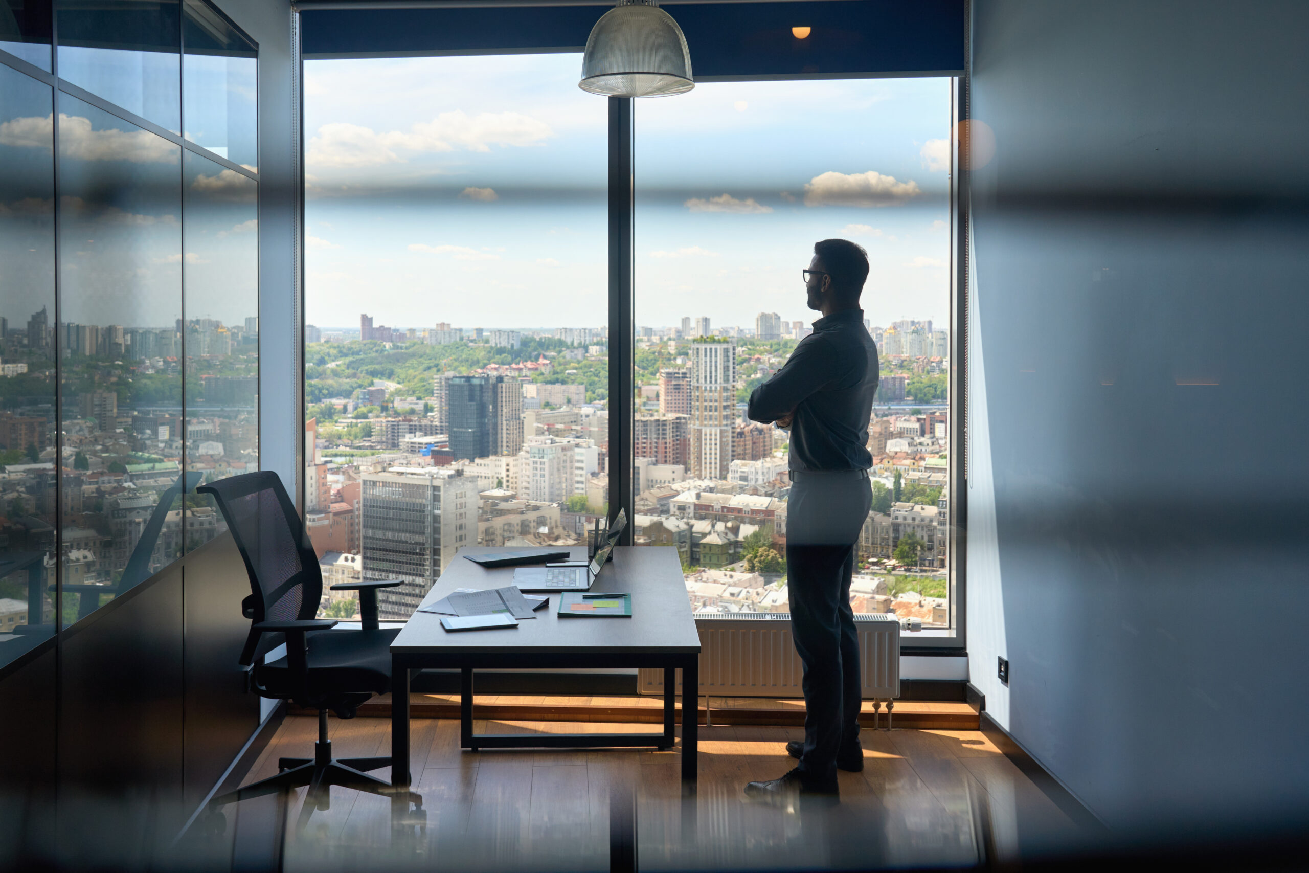Sales professional at his office, looking out the window